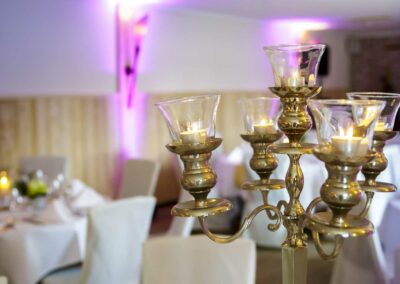 Antiker fünfarmiger Kerzenhalter aus Messing mit brennenden Kerzen in einem festlich gedeckten Restaurant.